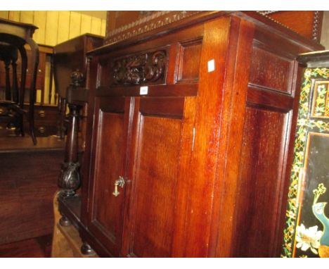 Victorian carved oak hall stand with a low carved back above a mask head drawer and cupboard door beside an umbrella and stic