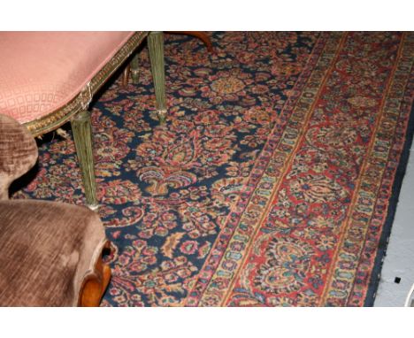 Large machine woven Persian pattern carpet with all-over floral design on a dark blue ground together with a similar rug