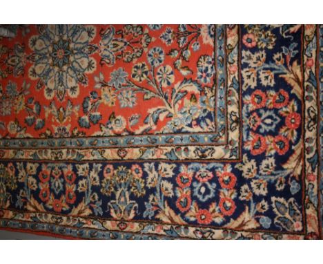 Large Persian style carpet having all-over floral design on a rust and blue ground with multiple borders, 9ft x 6ft