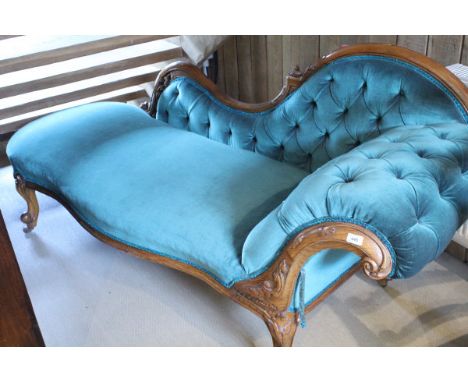 A Victorian walnut framed chaise longue with button back and shaped front with carved detail raised on cabriole legs to brass