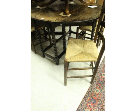 An oak drop-leaf dining table on bobbin supports, together with a set of six rush seated ladder back chairs, two further dini