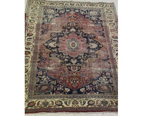 A Persian carpet, the central panel set with stylised flower head medallion on a pink and blue ground, with all-over floral d