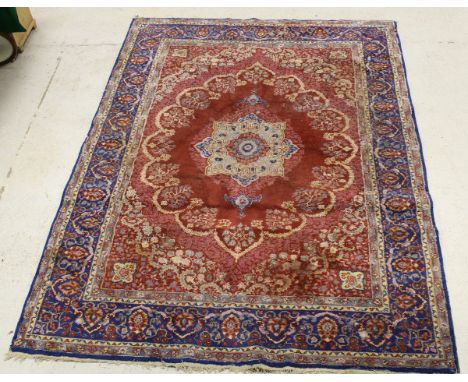 A persian carpet, the central panel set with stylised flower head medallion on a red ground within a stepped floral decorated