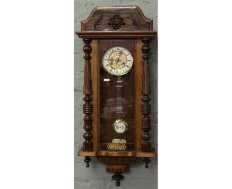 A Victorian eight day Vienna wall clock with brass and coloured enamel dial striking on a coiled gong.