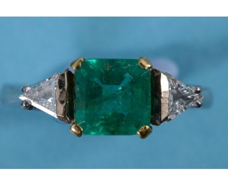 An 18ct gold, emerald and diamond ring, the central square cut emerald flanked by two trapeze cut diamonds, approx. ring size