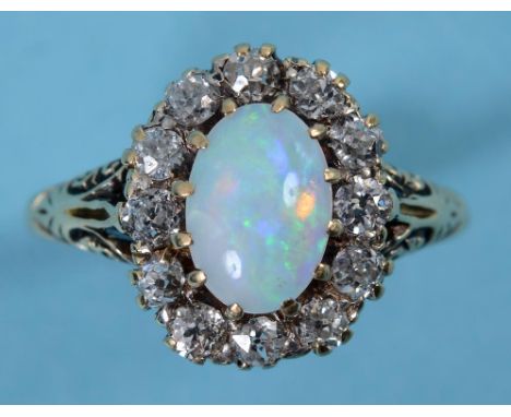 A yellow coloured metal ring, the central oval opal within a pierced surround set twelve diamonds  See inside back cover colo