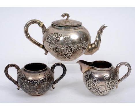 A Chinese silver coloured metal three piece tea set, with simulated bamboo handles, and embossed with prunus, approx. 20.1 oz