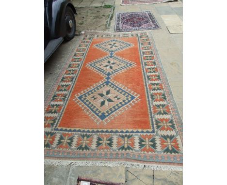 A Turkish carpet, decorated three central lozenges on a light red ground, within a multi border, 294 x 159 cm