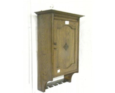 AN INLAID OAK MURAL SMOKER'S CABINET WITH DENTIL CORNICE AND PANELLED DOOR ABOVE A PIPE RACK, C1920