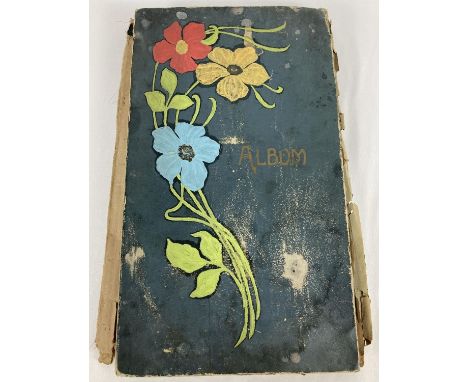An antique postcard album with floral detail to front containing a large collection of antique and vintage postcards and gree