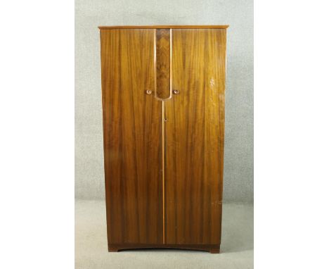 A circa 1950’s Uniflex figured walnut wardrobe the two doors opening to reveal hanging space, a mirror, shelves and two drawe