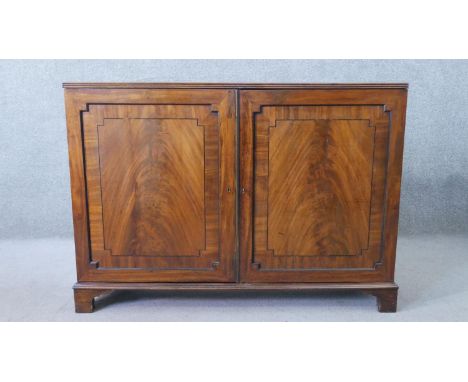 A George III flame mahogany side cabinet, with two crossbanded panel doors, enclosing shelves, on bracket feet. H.94 W.130 D.