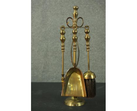 A set of brass fireside tools, on a stand, comprising tongs, a brush, a poker, and a scoop. H.43cm. 