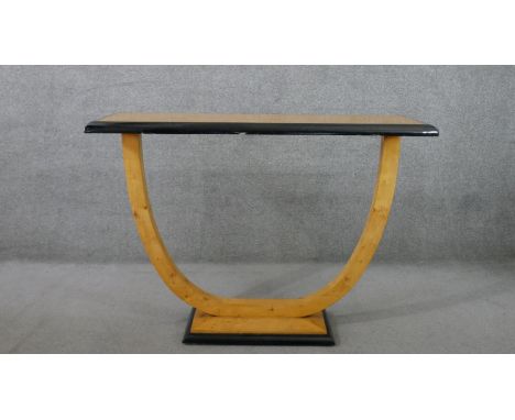 A contemporary Art Deco style console table, the rectangular top with a moulded ebonised edge, on a curved support, on a rect