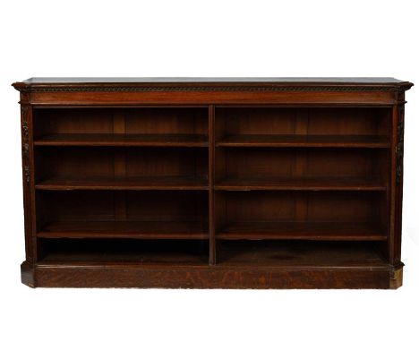 A Victorian oak dwarf bookcase flanked by carved canted sides and with adjustable shelves, 236cm wide, 43.5cm deep, 121.5cm h