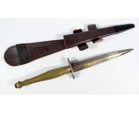 A Sykes Fairbairn type commando knife, with brass grip and shaped blade, in associated scabbard, length of blade 16.5cm. COND