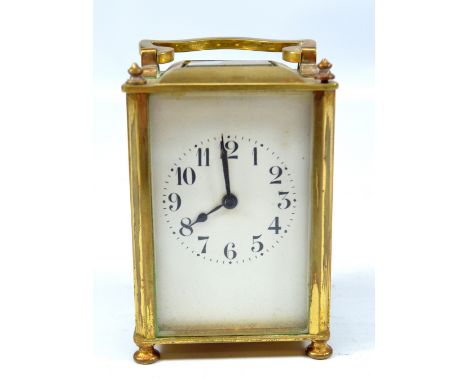 An early 20th century French brass carriage clock with swing loop handle above rectangular white enamel dial set with Arabic 