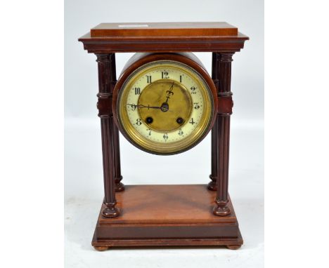 An Edwardian mahogany mantel clock with drum type movement set with Arabic numerals to the chapter ring supported by four flu