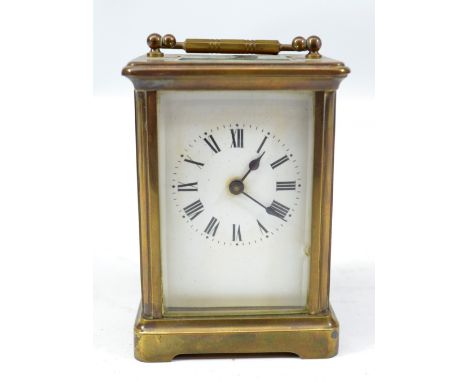 A circa 1900 French brass carriage clack with swing loop handle above white enamel dial set with Roman numerals and door numb