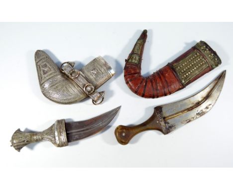 Two decorative jambiyas, one with white metal filigree decoration, curved blade and leather back to the scabbard, length 16cm