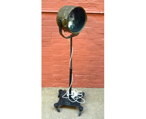 An early 20th century brass marine lamp now mounted on a central column and shaped rectangular base to castors, modelled as a