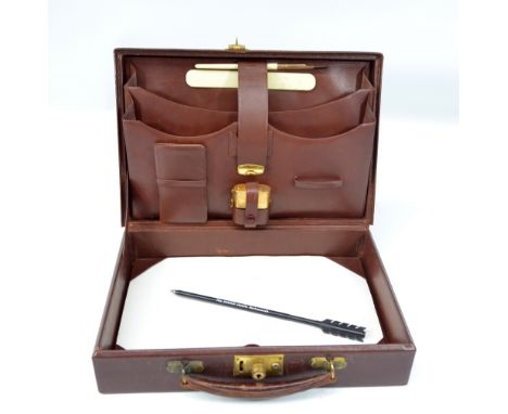 A small leather travelling case, the hinged lid enclosing a sectioned upper interior set with dip pen, paper knife, travellin