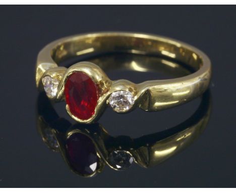 An 18ct gold ruby and diamond three stone ring,with an oval mixed cut ruby and two brilliant cut diamonds, partially rub set 