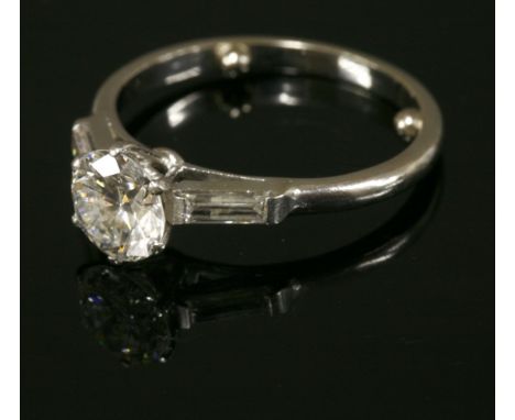 A single stone diamond ring,with baguette cut diamond set shoulders.  A brilliant cut diamond, with an estimated weight of ap