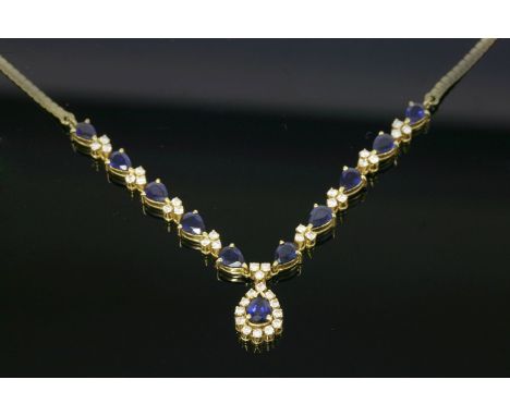An 18ct gold sapphire and diamond necklace,with an articulated 'V' shaped centrepiece.  A line of pear shaped sapphires, all 