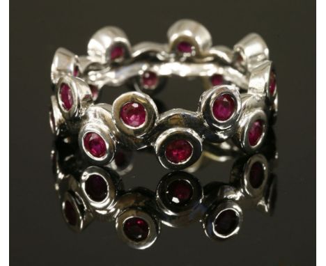 A Continential white gold, ruby band ring,with a central wavy section.  A continuous row of circular mixed cut rubies, rub se