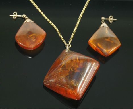 An amber matched pendant and earring suite, c.1930,with a cushion shaped amber cabochon containing insects to a gold 'V' shap