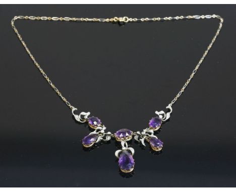 An Edwardian amethyst and diamond fringe necklace,with a centrepiece of three graduated oval mixed cut amethysts, all claw se