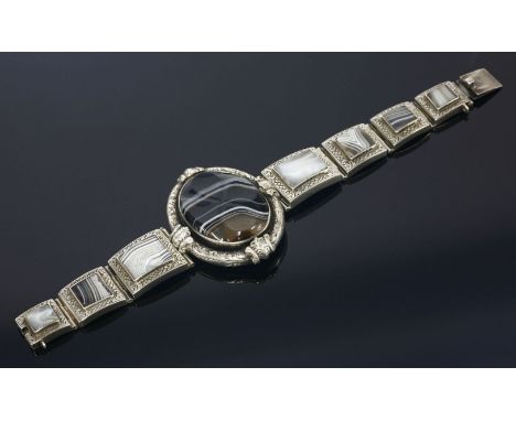 A Scottish sterling silver hardstone bracelet,with an oval centrepiece composed of a banded agate, carved oval plaque, to a c