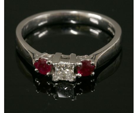 A platinum three stone diamond and ruby ring,with a central princess cut diamond, four claw set at the corners with a circula