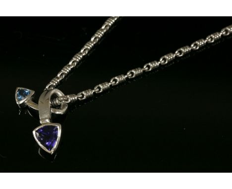 An 18ct white gold blue topaz and iolite crossover slide pendant,with a reel link chain