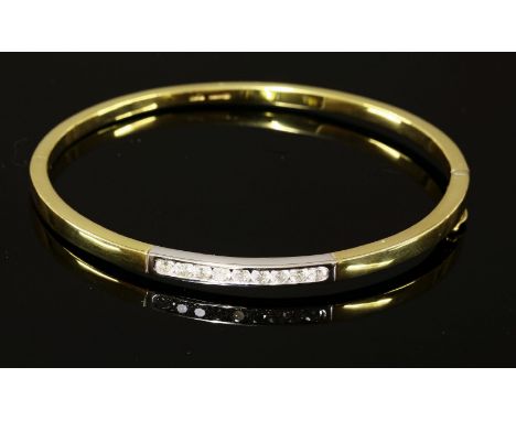 An 18ct yellow and white gold diamond set hinged bangle,with brilliant cut diamonds channel set in white gold to the centre o