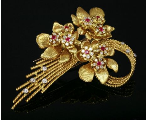 An 18ct gold ruby and diamond spray brooch, c.1950,by Sanitt and Stein.  Three flower heads with deeply scored petals each se