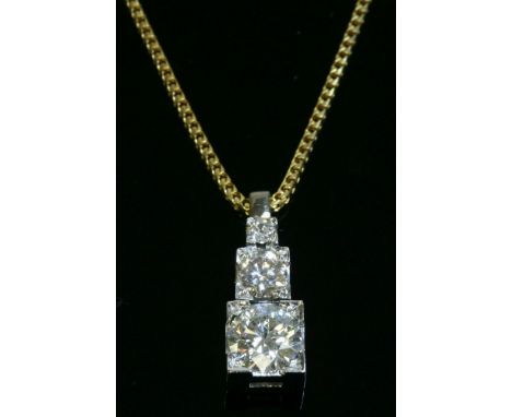 A yellow and white gold three stone diamond pendant,with three graduated diamonds, four claw set to graduated white box colle