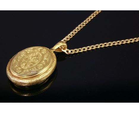 A late Victorian gold oval hinged locket,with recessed panels decorated with ivy leaves to a textured ground, suspended on a 