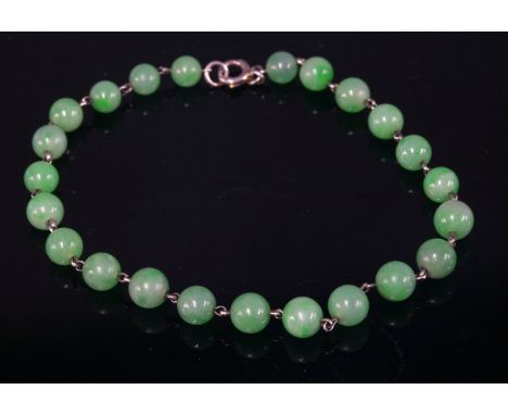 A uniform jade bead bracelet,with circular beads, 5.4mm diameter, all strung on to white wire with a small bolt ring clasp.  