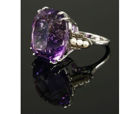 An amethyst and cultured pearl ring,with a cushion cut amethyst, double claw set at the centre.  Obus shoulders, each peg set