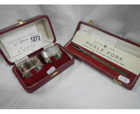 A cased pair of silver napkin rings and a cased silver pickle fork