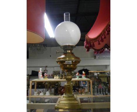 A brass oil lamp with shade and chimney
