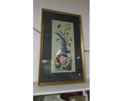 A tapestry picture of a blue bird, butterfly and flowers in a gilt frame