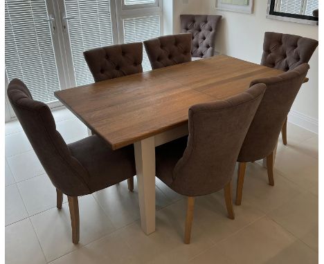 An extending dining room table with light oak top on white legs open to a centre leaf and eight button back chairs (H77cm W16