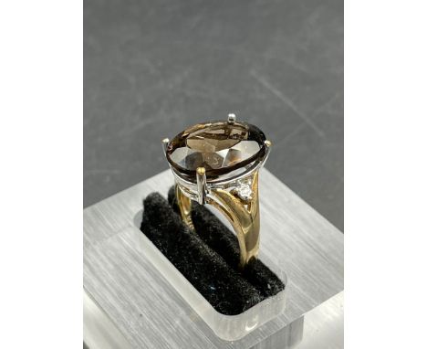 A smokey quartz and diamond ring, oval cut smoky quartz weighing on a 7.20ct claw set with a single cut diamond to each side,