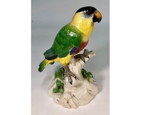 A Continental porcelain model of a parrot perched on a branch, raised on a rockly base, underglaze 'R' to base, 21.5 cm highD
