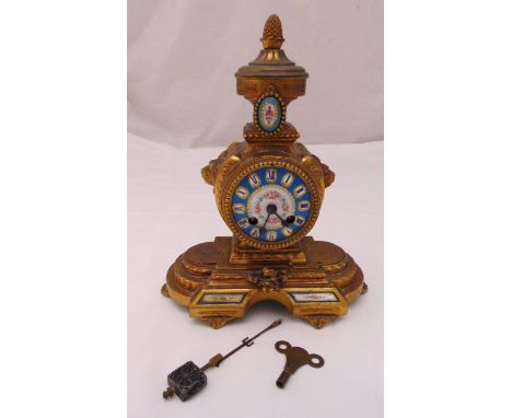 A French gilt metal mantle clock with Sevres panels and dial, Roman numerals, surmounted by pineapple finial on raised oval b