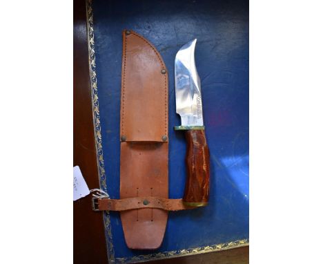 A Remington Dupont hunting knife, having 15cm blade, in leather sheath.