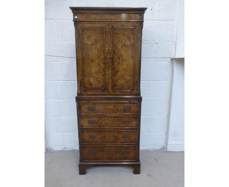 A reproduction walnut tallboy, the two door upper section enclosing a shaped fitted shelf,  above a brushing slide and four g